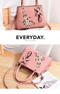 Detail showing pink leather handbag with white floral embroidery and gold hardware