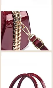 Close-up of wine red patent leather handbag featuring golden hardware and sturdy handles