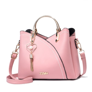 Detailed view of pink crossbody bag with metal ring handle and heart pearl charm