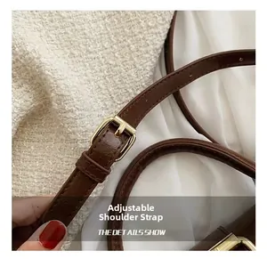 Detail showing adjustable brown leather shoulder strap with golden buckle of the handbag