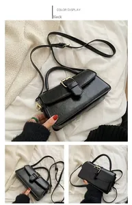 Detail view of black vintage leather handbag with gold metal clasp and adjustable strap