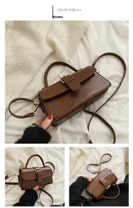 Detailed view of vintage brown leather handbag with metal buckle and adjustable strap