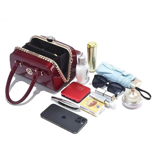 Glossy burgundy patent leather handbag with gold hardware and spacious interior view