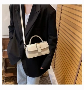 Close-up of cream leather flap handbag with gold metal hardware and top handle strap