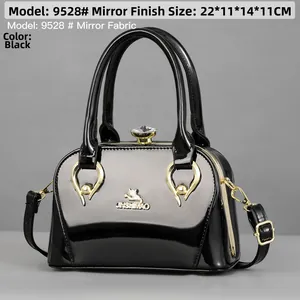 Detailed view of the black glossy patent leather handbag with sparkling rhinestone closure