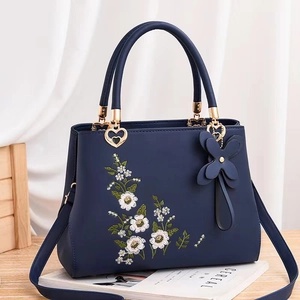 Navy blue faux leather handbag with floral embroidery and gold heart hardware