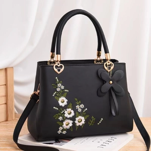 Elegant black embroidered handbag with floral pattern and golden heart metal buckle detail