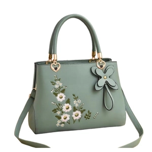 Light green faux leather handbag with white floral embroidery and butterfly pendant