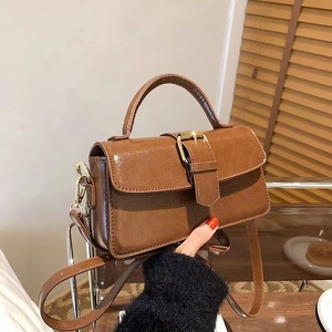 Detail view of brown vintage leather bag with polished gold buckle and adjustable strap