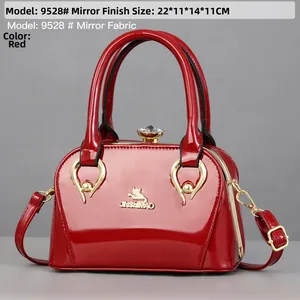 Detail of red mirror patent leather handbag with gold cat logo and diamond clasp