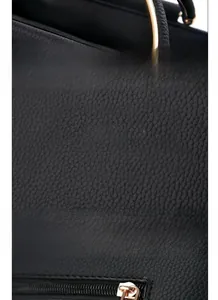 Vue détaillée du cuir grainé noir et de la poignée ronde dorée du sac à main pour femme