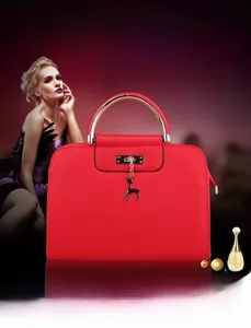 Close-up of red cowhide handbag featuring a golden metal handle and deer charm detail