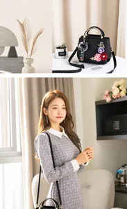 Details der schwarzen Ledertasche mit Blumenstickerei und Pelz-Pompon-Anhänger