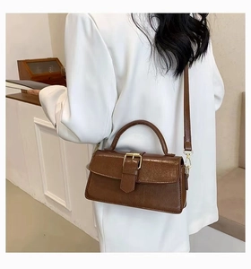 Deep brown retro handbag with glossy leather texture paired with a white blazer