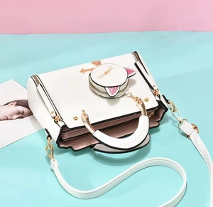 Vue détaillée du sac à main blanc avec poignée dorée et accessoire porte-monnaie chat