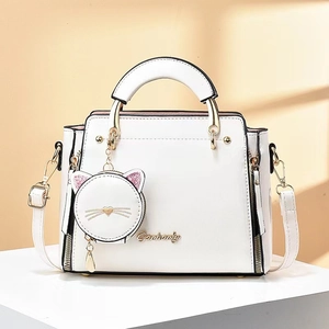 Détail d'un sac à main blanc en cuir avec logo doré et charm porte-monnaie chat