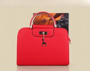 Red crossbody bag with metal ring handle and deer charm compared with A4 magazine
