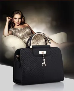 Detail of black lychee grain leather handbag with golden deer charm and diagonal stitching