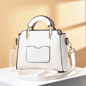 Détail du sac à main blanc en simili cuir avec bords noirs et boucles dorées