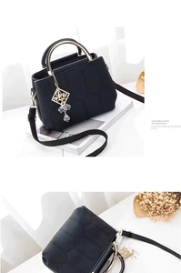 Close-up of black leather handbag with honeycomb quilting and gold metal ring handle detail
