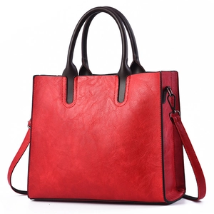 Detalle de bolso tote rojo en cuero PU con asas marrones y ganchos metálicos oscuros