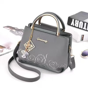 Sac seau gris avec gaufrage floral, poignée dorée et breloque cristal en décor lifestyle
