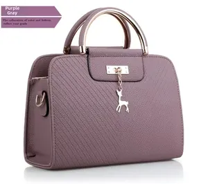 Detail view of purple-grey pebbled leather handbag with golden deer charm and handle