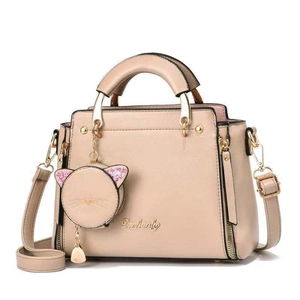 Sac à main chic beige avec détails dorés, poignée unique et pendentif chat mignon