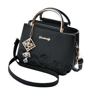 Sac seau élégant en cuir noir avec broderie rose et poignée dorée chic