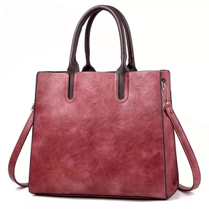 Primer plano de bolso tote rojo vino con textura de mármol y asas marrón oscuro