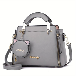 Détail d'un sac à main gris en cuir PU avec logo doré et charm de porte-monnaie chat mignon