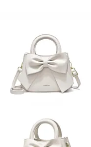 Détail d'un sac à main blanc crème avec un grand nœud et des ferrures en métal doré