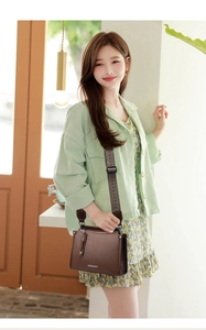 Detail of dark brown leather crossbody bag with wide geometric pattern strap and zipper