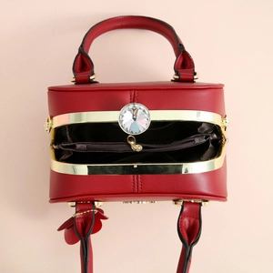 Détail de sac à main rouge foncé avec trois compartiments et fermoir doré en strass