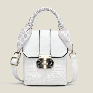 Détail du sac blanc gaufré crocodile avec boucle dorée et foulard en soie sur la poignée