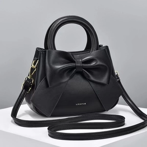 Détail du sac à main en cuir noir avec grand nœud et finitions métalliques dorées