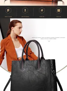 Bolso tote negro grande con textura plisada y correa ajustable usado por una modelo