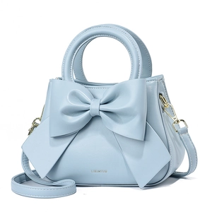 Détail du sac à main en cuir bleu clair avec un grand nœud et une bandoulière réglable