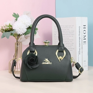 Gros plan d'un sac en cuir vert foncé avec logo chat doré et fermoir en cristal