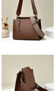 Detail of a brown leather shoulder bag featuring a jacquard woven strap and retro finish