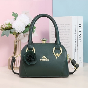 Détail du sac en similicuir vert foncé avec breloque rose et fermoir gemme