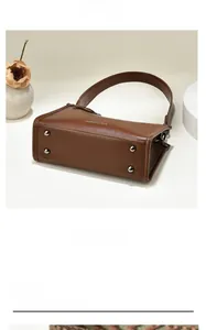 Detail view of brown leather bag bottom with four silver metal feet and fashion logo