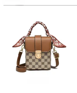 Detail of vintage square handbag featuring brown leather trim and printed silk scarf handle