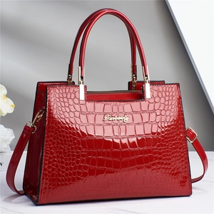 Détail du sac à main rouge en similicuir croco avec logo doré et doubles poignées de luxe