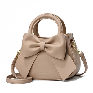 Sac à main élégant abricot avec un grand nœud décoratif et détails métalliques dorés