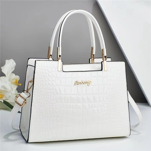 Détail d'un sac à main blanc motif crocodile avec logo doré et poignée ronde
