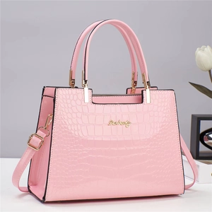 Détail de la texture crocodile rose et logo doré sur le sac à main élégant pour femme
