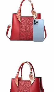Dettaglio borsa rossa con goffratura floreale e confronto dimensioni con telefono