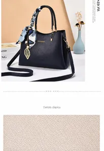 Dettaglio della borsa blu navy in pelle a grana con foulard di seta e ciondolo a foglia