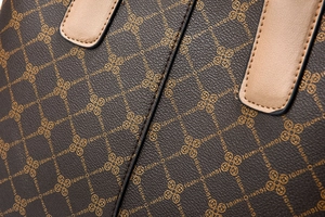 Macro shot of IGUREI monogram pattern on dark brown pebbled leather with precise stitching